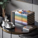 A stack of beautifully illustrated BL manhwa books is neatly arranged on a modern coffee table. Beside the stack, two steaming cups of coffee add a cozy ambiance to the scene. This setting provides a perfect backdrop for BL manhwa recommendations, inviting readers to explore the captivating stories within these colorful volumes.